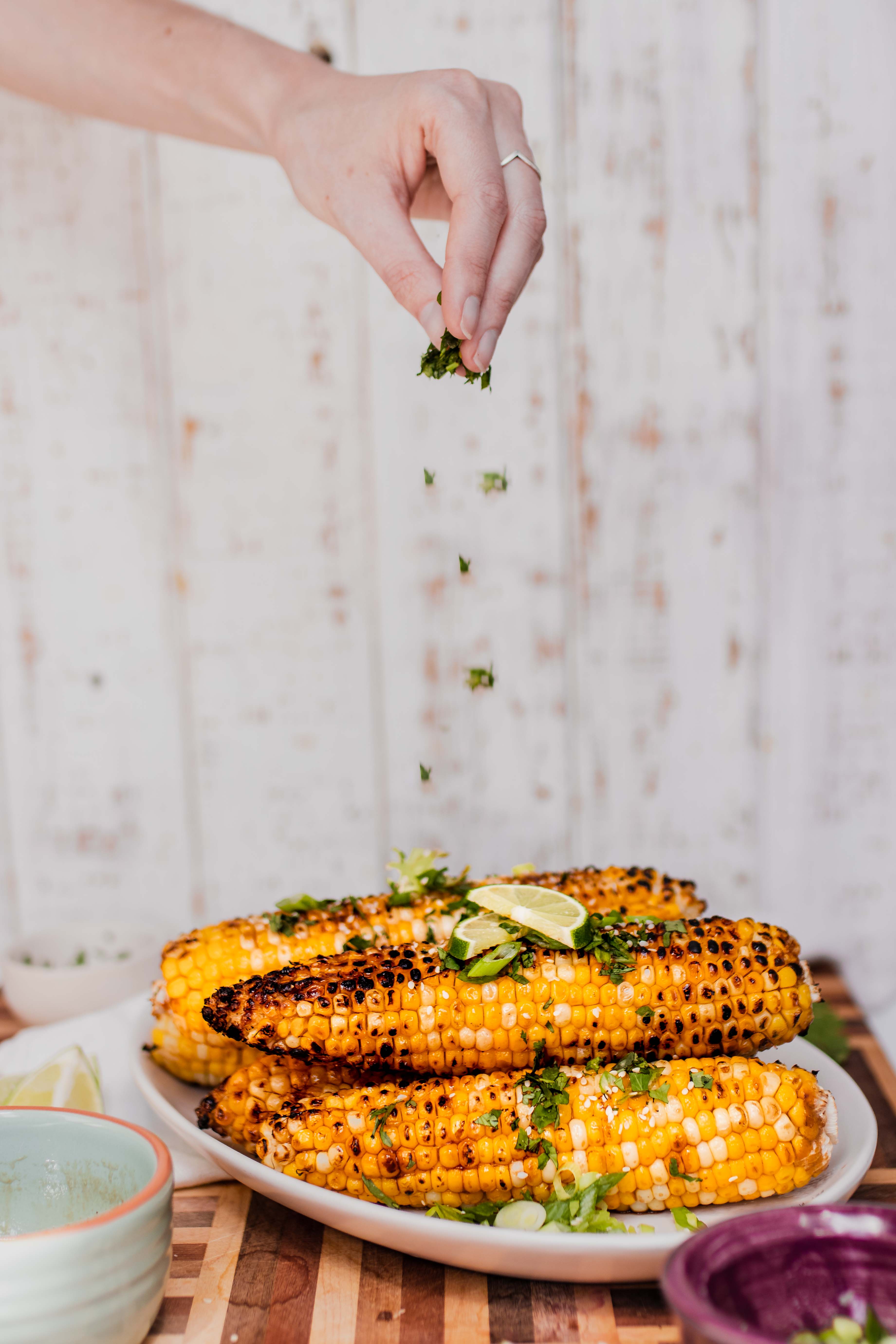 sesame glazed corn on the cob with cilantro being sprinkled over top