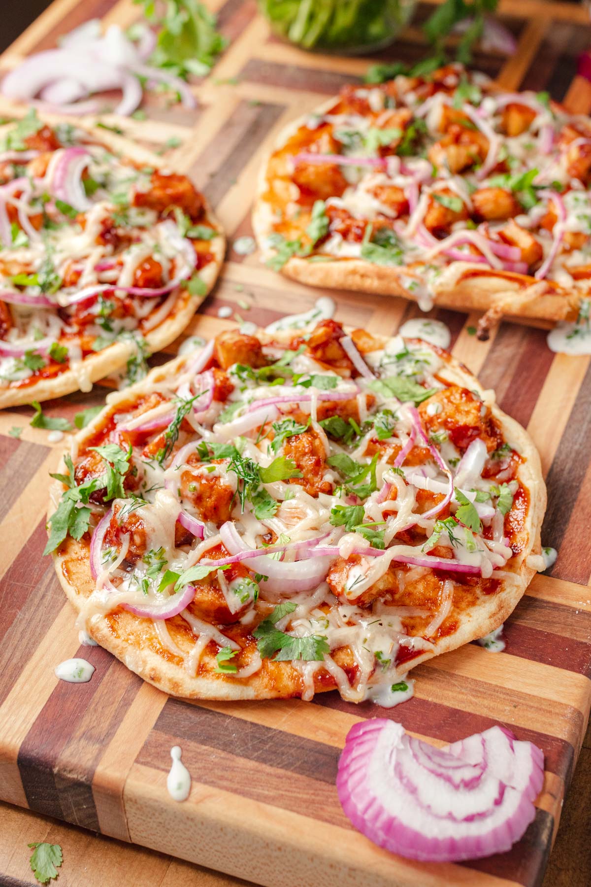 45 degree angle picture of a pita with vegan bbq chicken, vegan cheese, red onion, cilantro and drizzled with vegan ranch