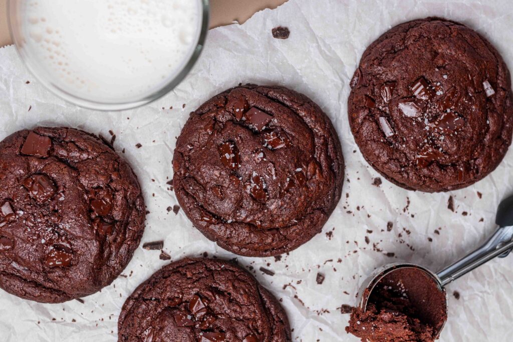 Top-down image of double chocolate brownie cookies on a piece of parchment. 